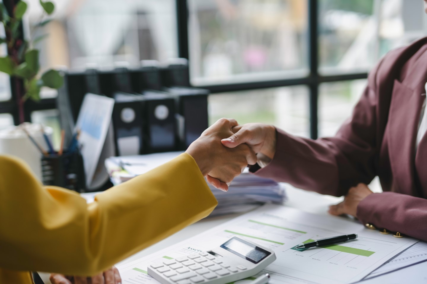Two women shaking hands — partnership and accountability.